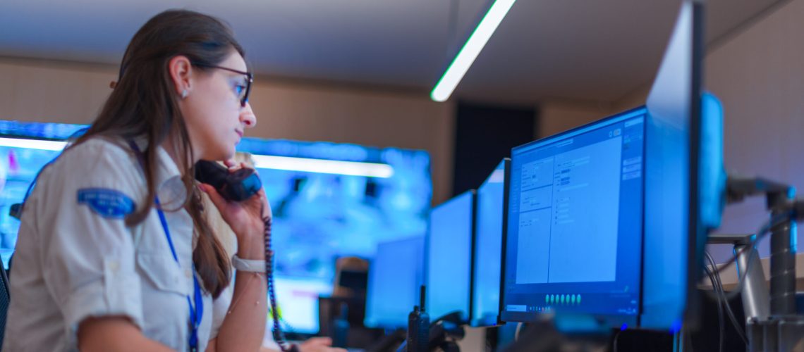 Female security guard operator talking on the phone while watching the computer ( cctv monitors ).